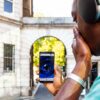 A young man is holding his smartphone and watching a scary scne from Dr Jekyll and Mr Hyde on the screen. He is covering his mouth with his hand