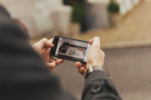 A man is holding a smartphone. On the screen a puzzle is visible