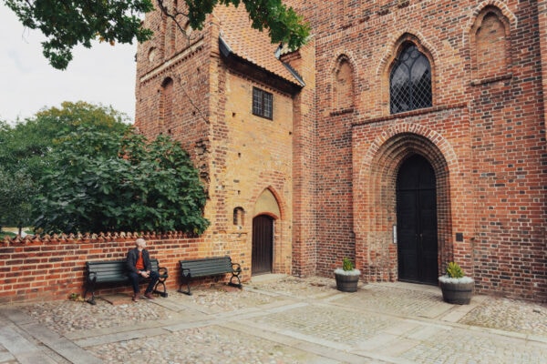 A man is sitting on a bench next to Ystad klosterkyrka