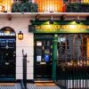 An exterior picture of 221B Baker street with a black door and the windows of the museum next to it.