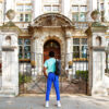 A young man walking the Dr Jekyll and Mr Hyde tour in London is standing in front of a large stone building. He has his back towards us.