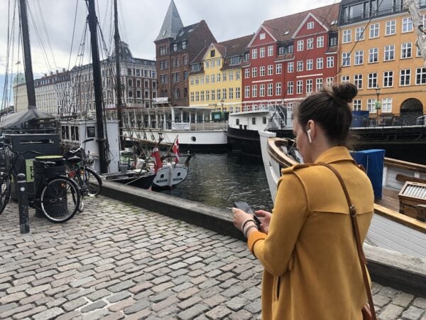 A woman in a yellow coat is walking through Nyhavn
