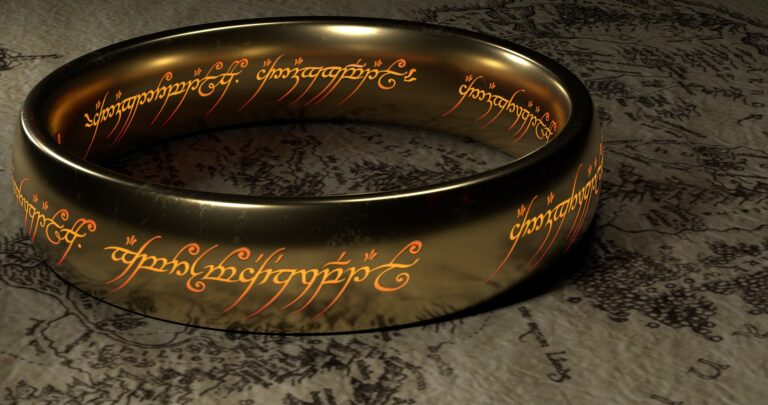 A golden ring, with elven inscriptions, is placed on a map.