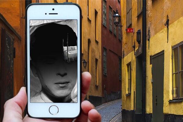 A hand is holding a mobile phone with a sketch of a man in black and white.