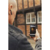 A man standing in front of a half timbred house is holding up his smartphone