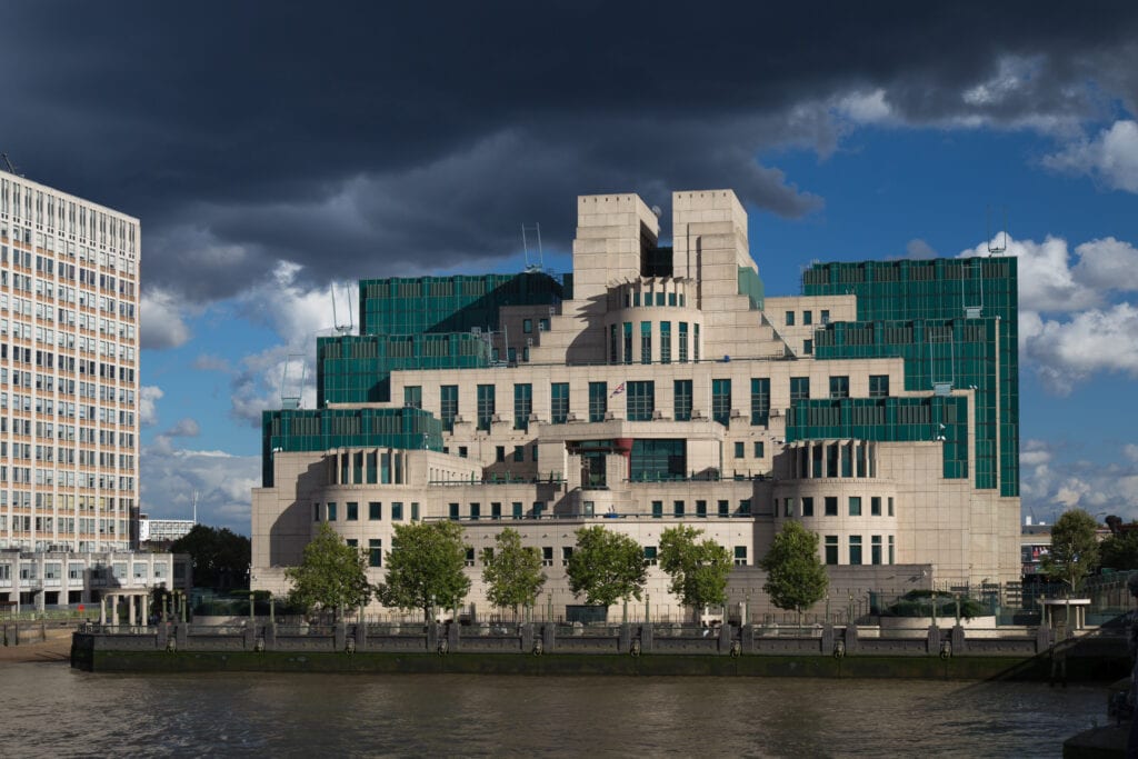 An exterior picture of the SIS building. It is large and gray with a green roof