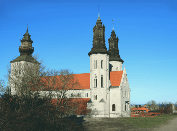 A photograpgh of Sankta Maria cathedral taken from a distance. The church is white with dark colored spires. The sky is very blue.