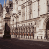 An exterior photo of the Royal Courts of Justice, with a statue of a dragon in front