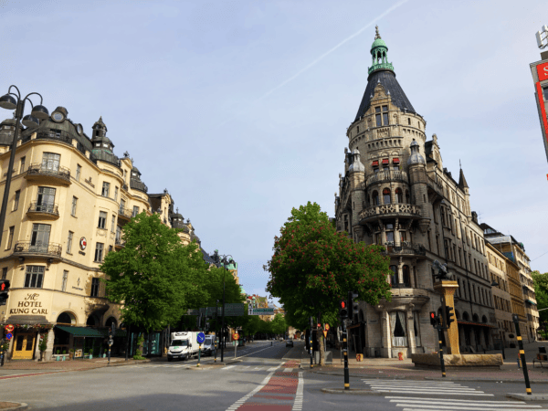 A photograph of Stureplan in Stockholm. The neo gothic buildings stretch upwards toward a blue sky.